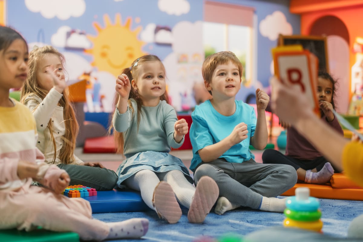 Cheerful Preschool Educator Playing and Creatively Studying with Multiethnic Kids in Kindergarten. Small Adorable Children Getting Basic Reading and Writing Skills, Learning Alphabet